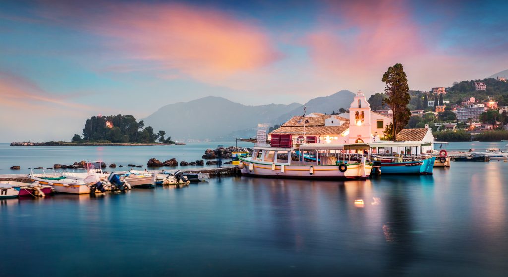 Impressive sunset view of Vlacherna Monastery. Colorful evening cityscape of Kerkira town, capital of Corfu island, Greece, Europe. Great spring seascape of Ionian Sea. Traveling concept background.
