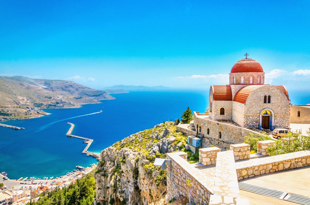 Amazing view on remote church with red roofing on the Cliff of the sea, Greece